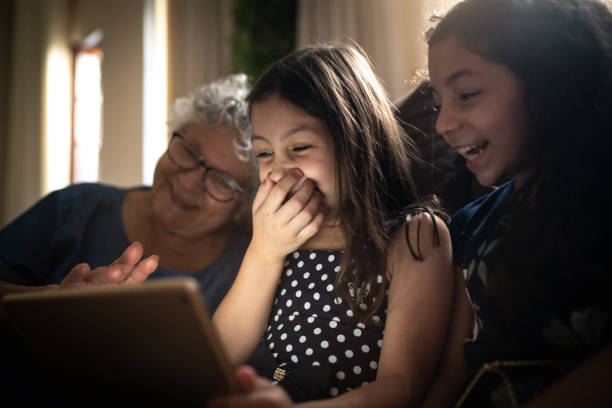 nonna e nipote usano il tablet digitale a casa - ipad senior adult facebook sofa foto e immagini stock