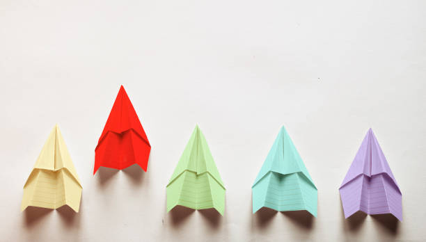istock Human hand coming up with a paper plane and playing with it isolated on a black colored background. 1249408808