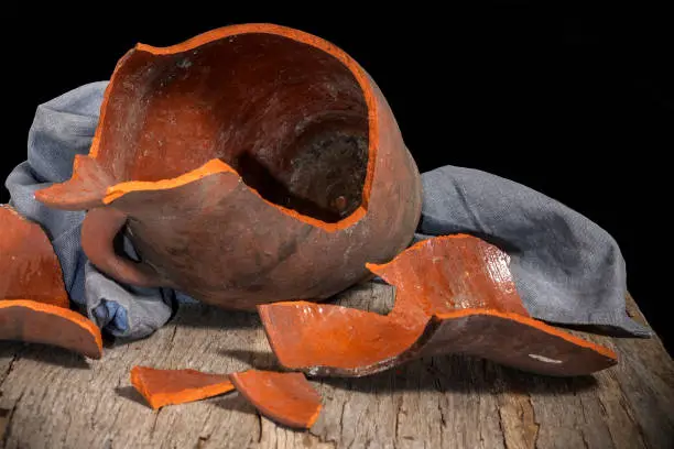 Broken clay jug on a wooden table.