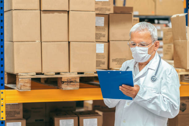 Senior doctor checking medical stock in a warehouse Senior doctor checking medical stock in a warehouse medical supplies stock pictures, royalty-free photos & images