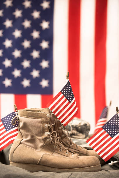 American Veteran's Day theme with military boots, hat, USA flag. USA military boots, hat and dog tags with American flag in background. No people in this US Memorial Day or Veteran's Day image. usa flag shoes stock pictures, royalty-free photos & images