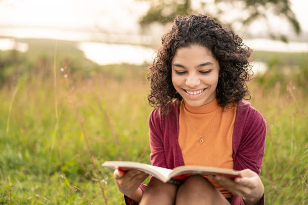 istock Teenager reading a book sitting on the grass 1249441365