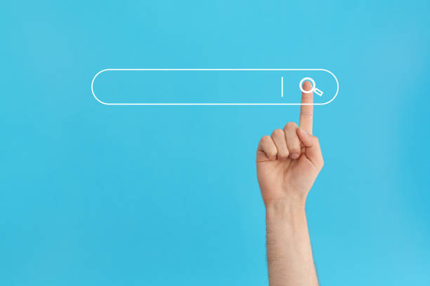 Finger presses the search button in the search bar on a blue background. stock photo