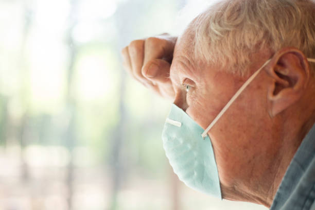 istock Senior man wearing COVID-19 mask.  He sits alone on bench outside. 1249442468