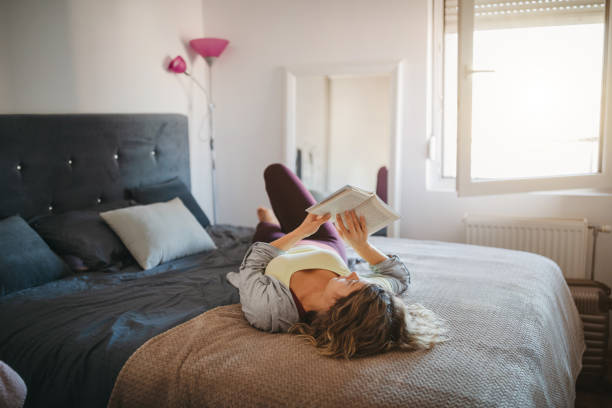 istock Young woman reading book at home 1249444098