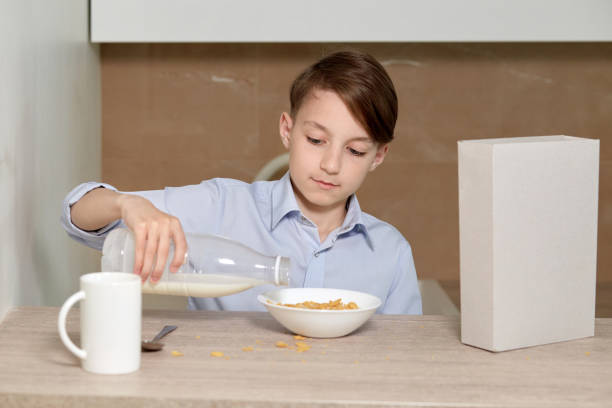 istock A boy sits in the kitchen and pours milk into cornflakes. 1249447790
