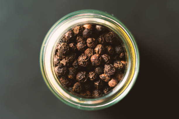 istock Black peppercorns in glass jar 1249450054