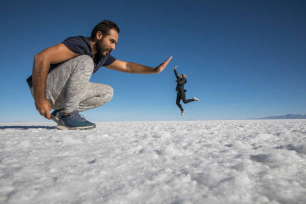 istock Couple playing with perspective in desert salt flats 1249450376