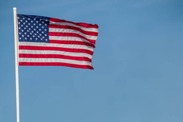 istock American flag flying in a blue sky 1249450445