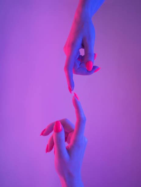 istock Two female hands with bright manicure reaching to each other. 1249453252