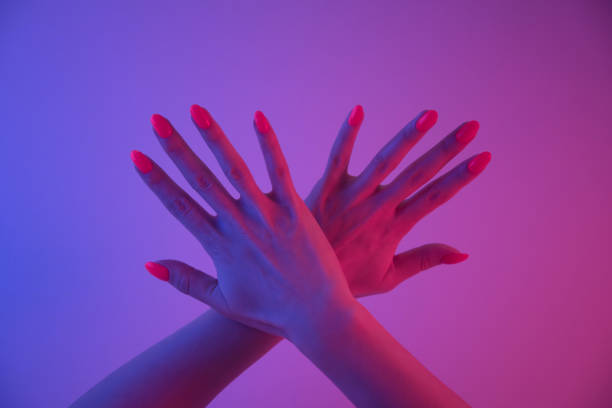 istock Female hands with bright orange color manicure in neon light. 1249453543