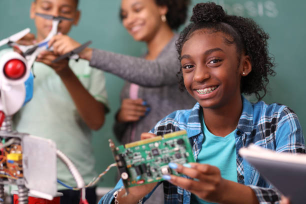 Junior high school age school students build robot in technology, engineering class. Junior high school age, African American teenage girl works on building a robot in technology class in school classroom setting.  STEM topics. high school high school student science multi ethnic group stock pictures, royalty-free photos & images