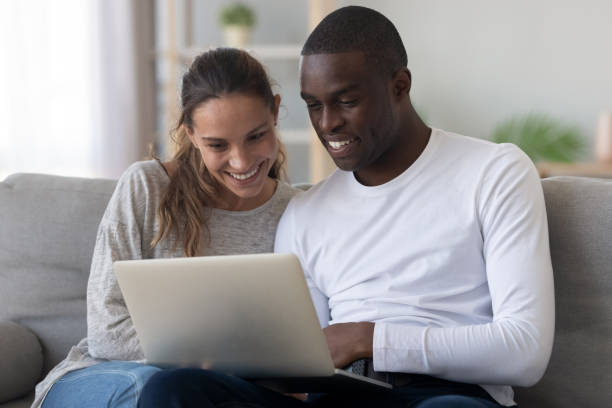istock Happy international couple relax at home using laptop 1249459698