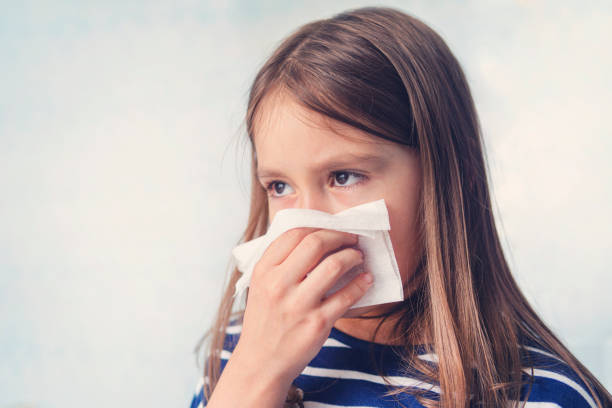 little girl with handkerchief. a cold girl blows her nose in a white rag on a blue background. diseases and colds. rhinitis snot runny nose stuffy nose. medical concept - allergy sneezing cold and flu flu virus imagens e fotografias de stock