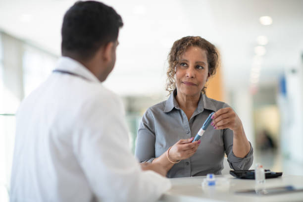 Diabetes consulting A woman discusses with her doctor about possibilities for diabetes treatment in a well lit medical facility. insulin stock pictures, royalty-free photos & images