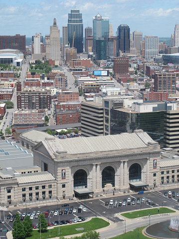Kansas City, United States - May 17, 2015: The skyline of Kansas city spreads out to the horizon behind Kansas City Union Station.  A magnificent Beaux-Arts building established in 1914, and shuttered by 1985, it was restored during the 1990s, hosting museums and shops.  In 2002, Amtrak train service returned.  The building was added to the National Register of Historic Places in 1972.