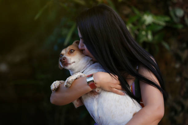 Adult brunette white woman playing with her dog pet