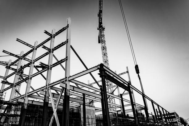 istock Gritty construction image of steel framing and construction crane on building site in monochrome. 1249473149