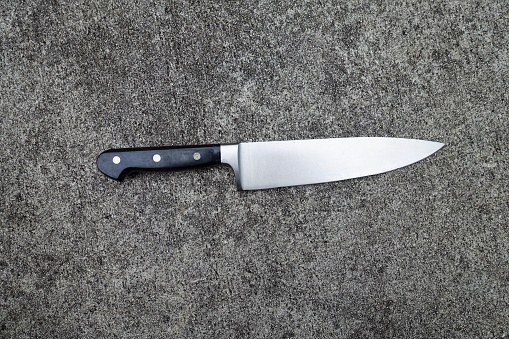 Kitchen knife on concrete background. Weapon or kitchen utensil.