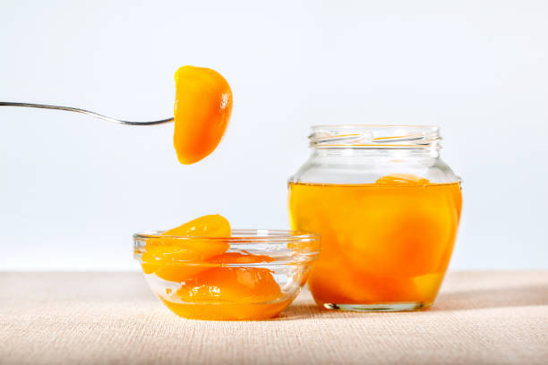 istock Canned peaches in glass jar and bowl on table. Space for text. 1249491829