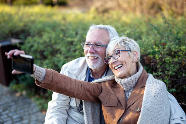 istock MAture couple taking selfie by mobile phone while sitting on bench in public park 1249498796