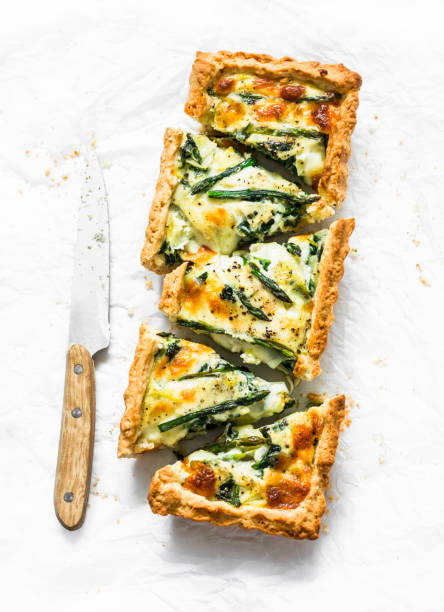 Tart with asparagus, mozzarella and spinach on a light background, top view