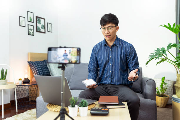 istock Asian man in headphones writing notes in notebook watching webinar video course studies via laptop at home lecture study online, E-learning concept 1249501953