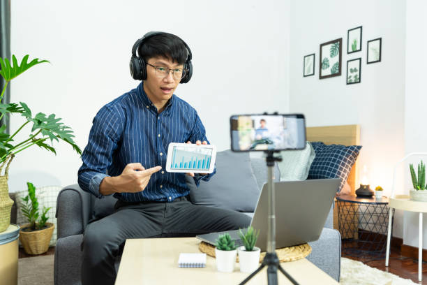 istock Asian man in headphones writing notes in notebook watching webinar video course studies via laptop at home lecture study online, E-learning concept 1249503576