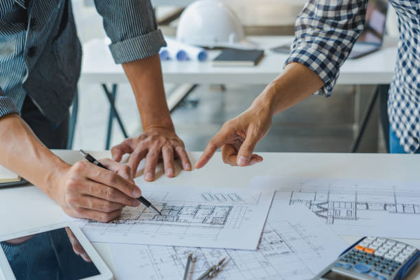 istock engineer Hand Drawing Plan On Blue Print with architect equipment discussing the floor plans over blueprint architectural plans at table in a modern office 1249504208