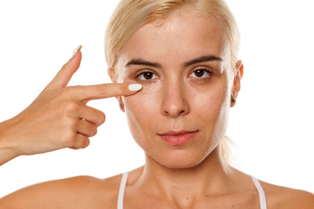 istock woman applying concealer under her eyes 1249506439