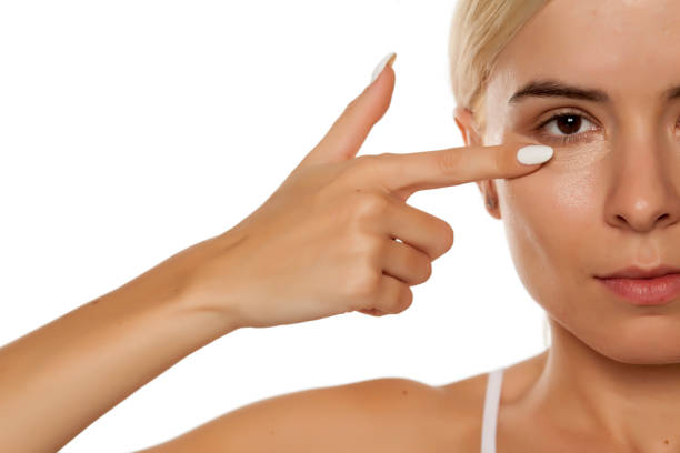 istock woman applying concealer under her eyes 1249506440
