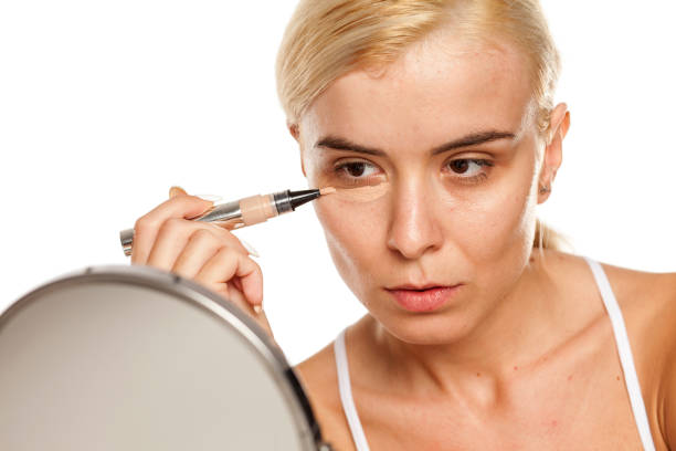 istock woman applying concealer under her eyes 1249506448