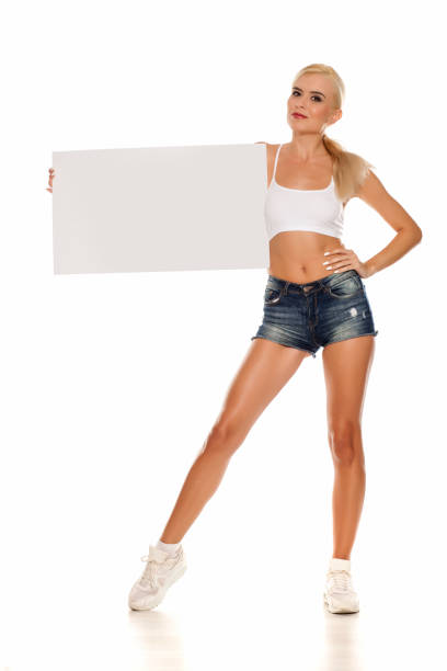 istock woman posing in short jeans and holding empty board 1249506490