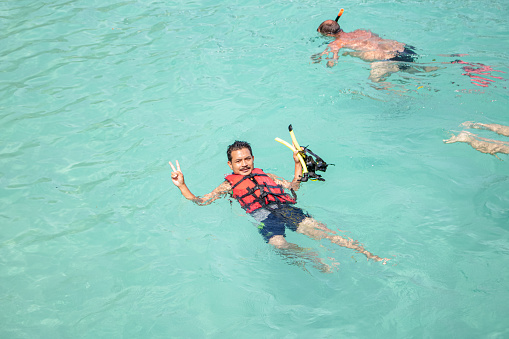 Young man snorkeling in clean water over coral reef. A man wear \nLife jacket.