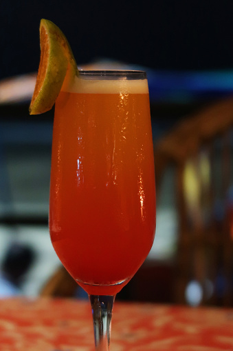 Stock photo showing a Sex on the Beach orange and vodka based alcoholic cocktail, stood on a wooden table in an Indian restaurant. Non-alcoholic versions of cocktails are often referred to as mocktails.