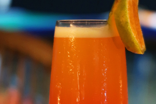 Stock photo showing a Sex on the Beach orange and vodka based alcoholic cocktail, stood on a wooden table in an Indian restaurant. Non-alcoholic versions of cocktails are often referred to as mocktails.