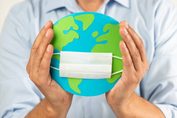 istock Hand Holding Globe And a Face Mask 1249509539