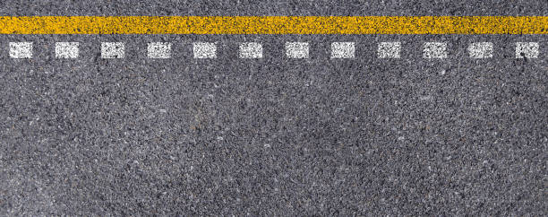 istock Double yellow and white lines on asphalt street roadway surface texture background. 1249510349