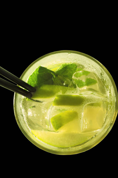 Drink with slice of lemon, apple, mint and ice in glass.