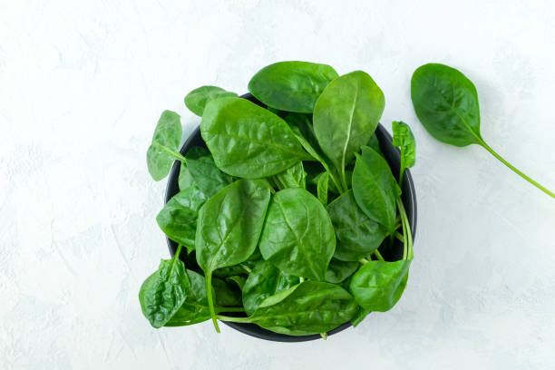 istock Fresh spinach leaves in a black bowl and on a light surface 1249514102