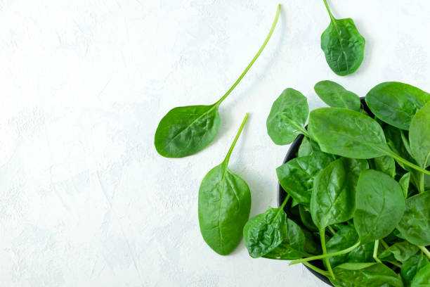istock Fresh spinach leaves in a black bowl and on a light surface 1249514227