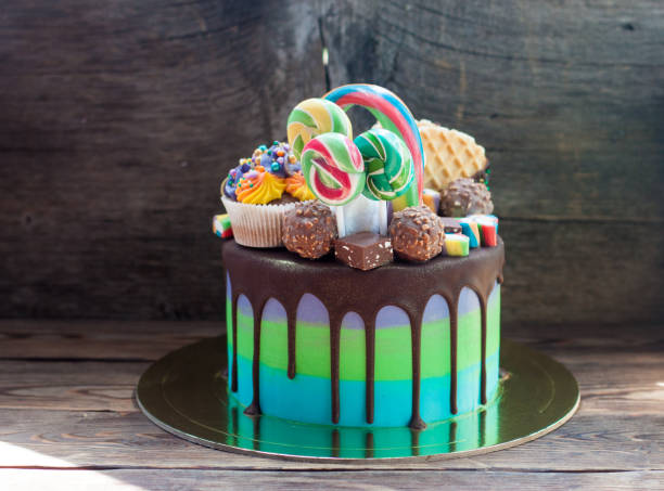 pastel brillante de cumpleaños de color verde y azul decorado con chocolate, pasteles, piruleta, gofres y magdalenas. - gateaux cake birthday decorating fotografías e imágenes de stock