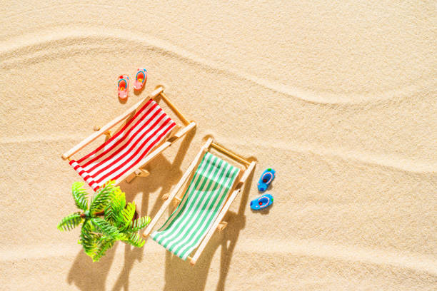 vue aérienne de deux chaises longues, transat, salon, tongs, palmier sur la plage de sable fin. concept d’été et de voyage. minimalisme - beach tropical climate palm tree deck chair photos et images de collection