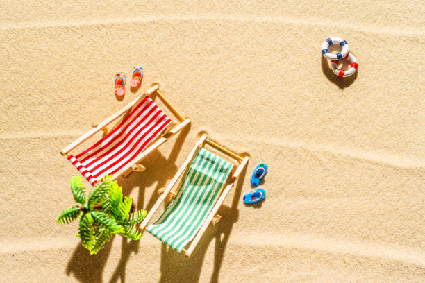 vue aérienne de deux chaises longues, transat, salon, tongs, lifebuoy, palmier sur plage de sable fin. concept d’été et de voyage. minimalisme - beach tropical climate palm tree deck chair photos et images de collection