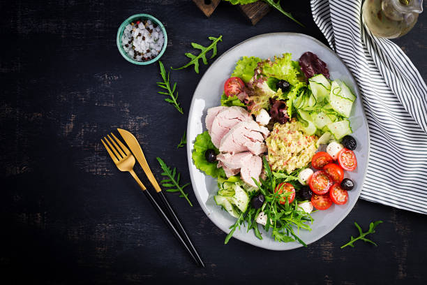 istock Ketogenic diet. Dinner dish with boiled pork meat, avocado guacamole, tomatoes, cucumbers, mozzarella cheese, black olives  and arugula. Detox and healthy concept. Keto food. Overhead, top view 1249520842