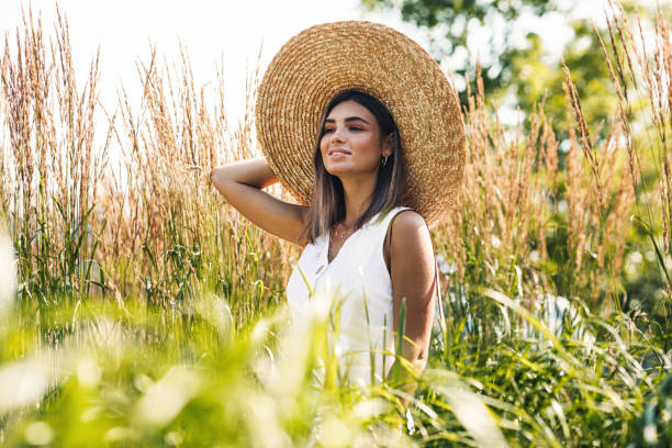istock Young blond woman holds her straw hat while walking on the field 1249524290