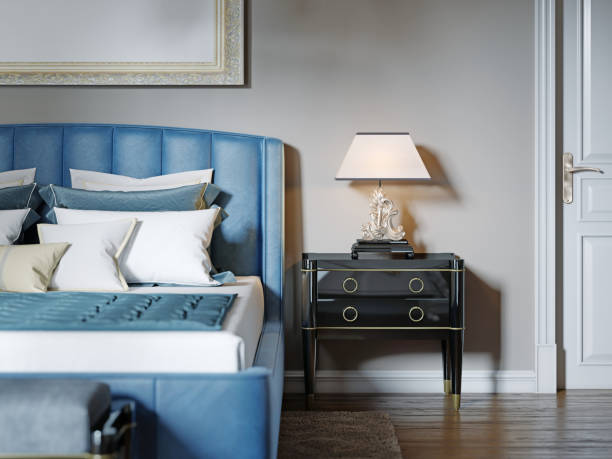 istock Black lacquered bedside table with table lamp and silver curly stand. The lampshade is square in shape. 1249525139