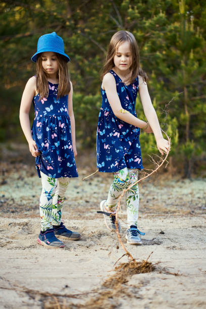 istock little girls in dresses pull the root on the forest road 1249525173