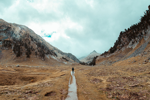 Lonely man walking in nature of Benasque Valley, surrounded by the highest peaks in that range, located in the heart of the Pyrenees, Aragón, Spain