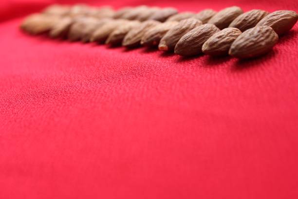 Almonds lined with a line on a red background. Almonds closeup with place for text. Nuts and dried fruits, healthy nutrition.